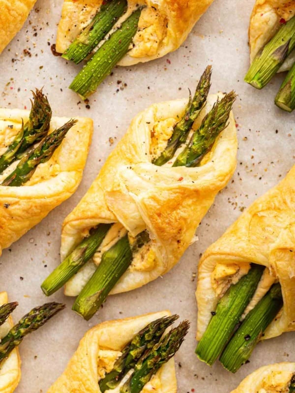 Macro shot of asparagus puff pastry tarts on parchment paper.