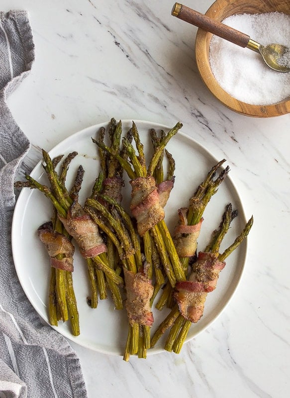 Bacon wrapped asparagus spears on white plate.