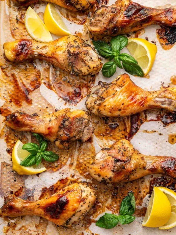 Balsamic chicken drumsticks on sheet pan with lemon wedges.