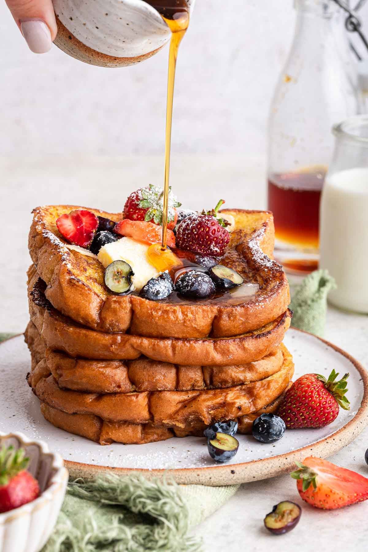 small-batch-french-toast-for-two Stack of brioche French toast with berries and syrup pouring over the top.
