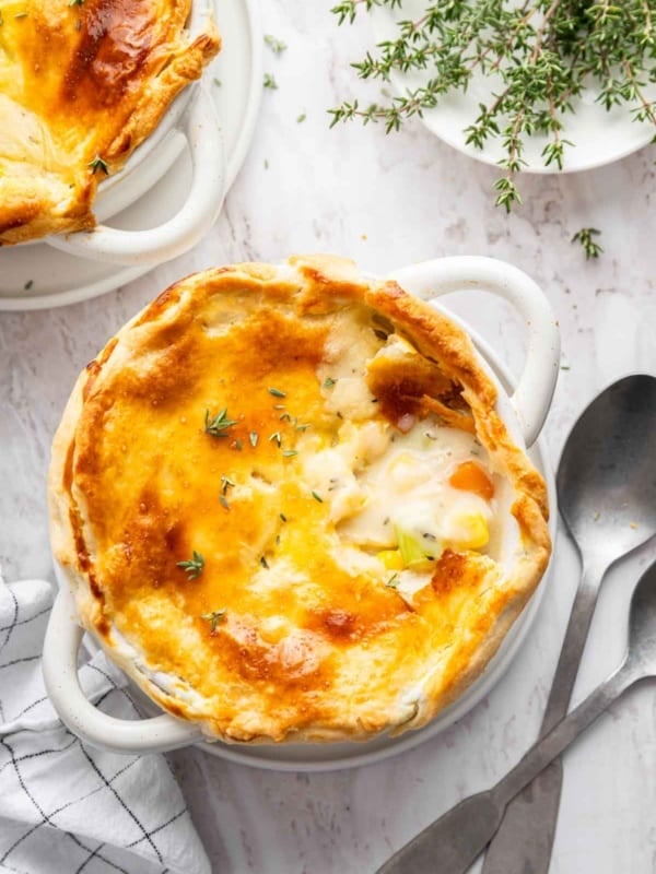 Vertical image of chicken pot pie for two with bite missing from crust.