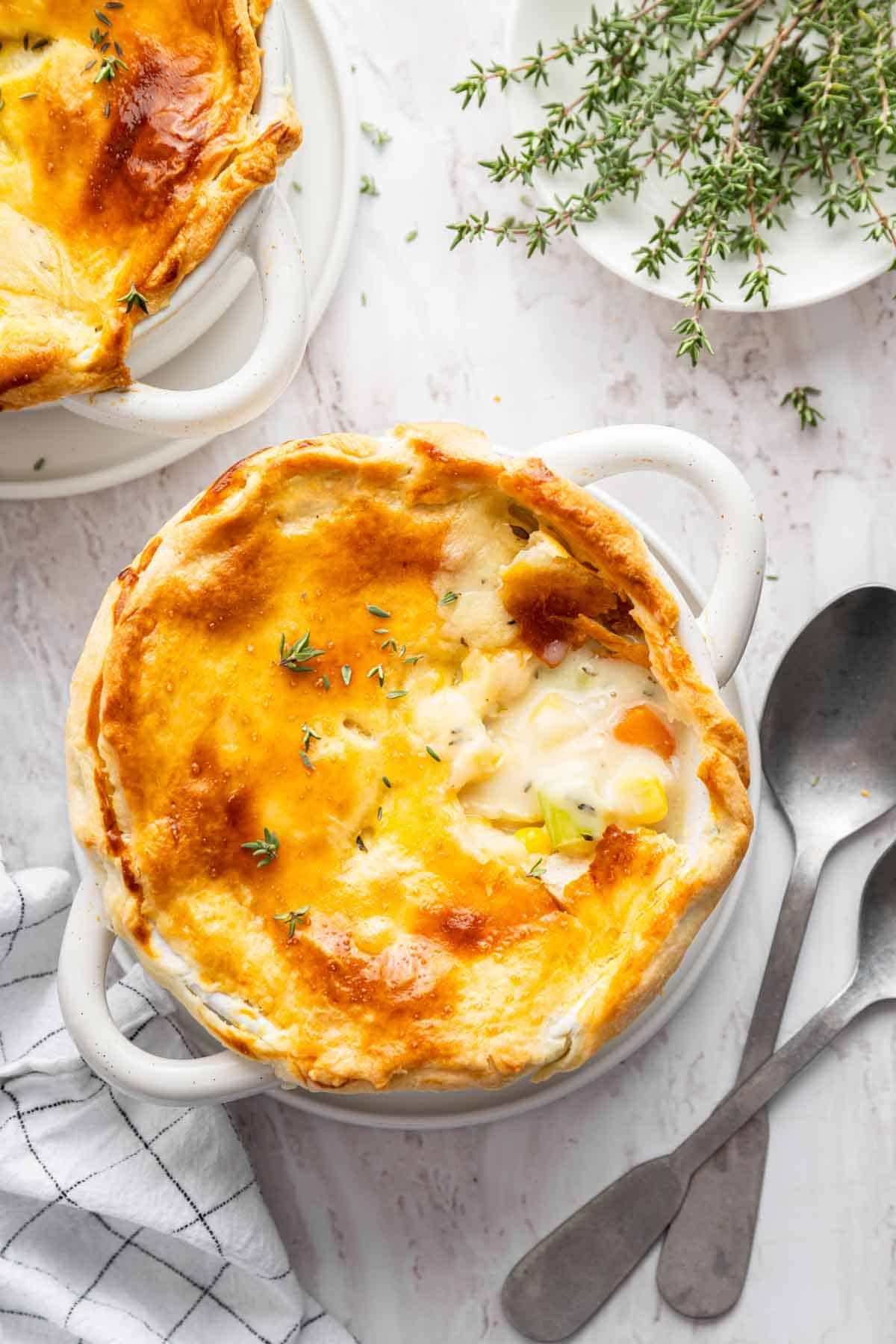 Vertical image of chicken pot pie for two with bite missing from crust.