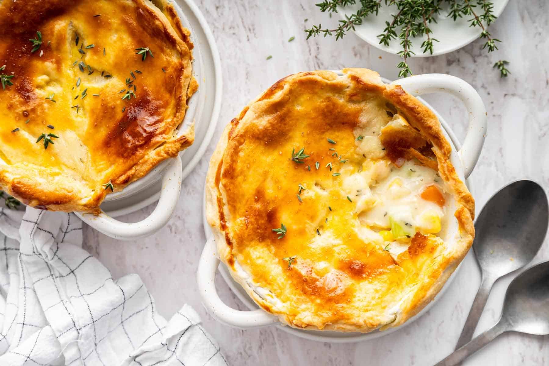 Two oversized bowls of chicken pot pie topped with pastry crust.