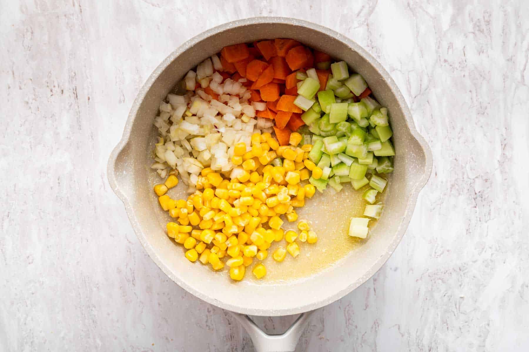 White skillet with chopped vegetables for sautéing.