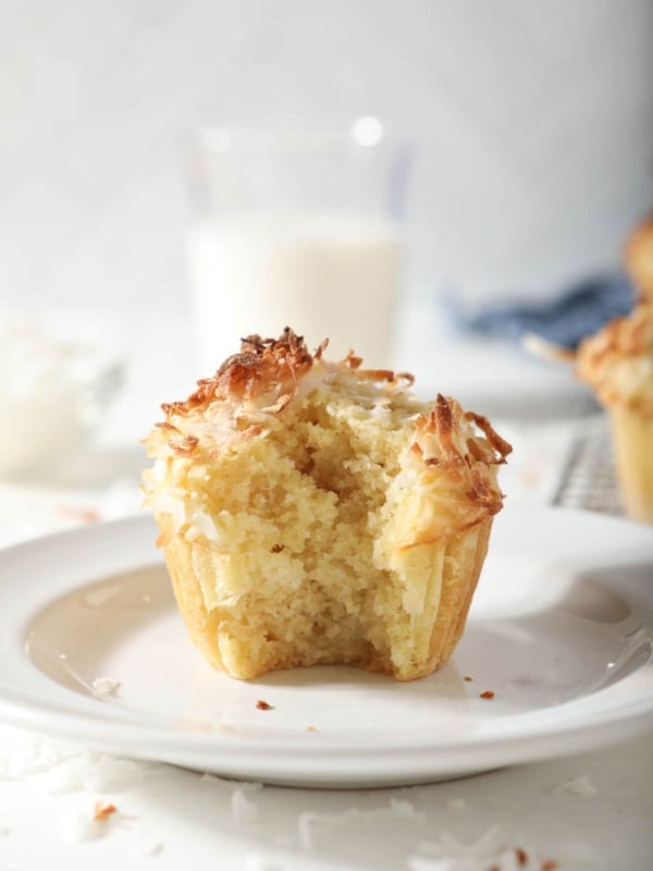 Coconut muffin on plate with bite missing.