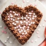 Vertical image of chocolate heart cake with sprinkles on top.