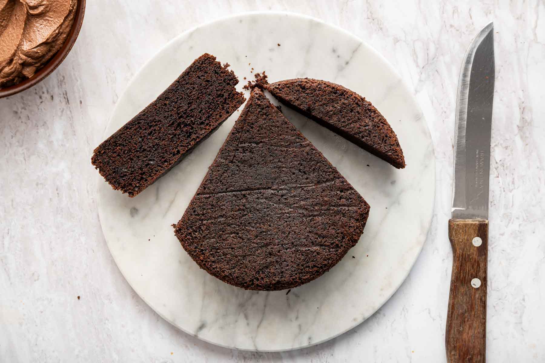 Round cake cut into three pieces on marble board.