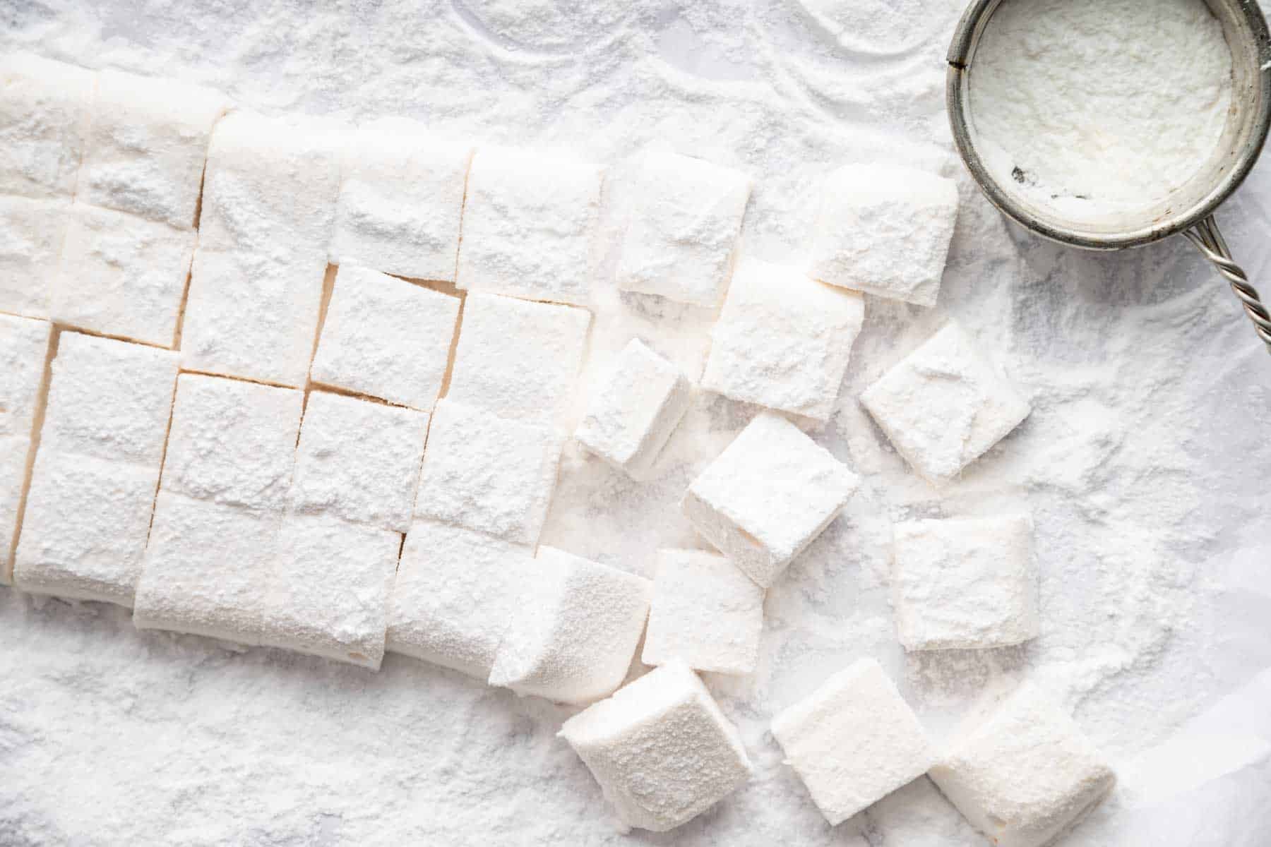 Horizontal image of freshly cut homemade marshmallows dusted in powdered sugar.