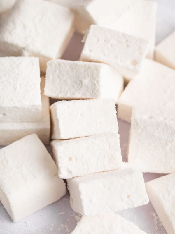Pile of square homemade marshmallows on a white board.