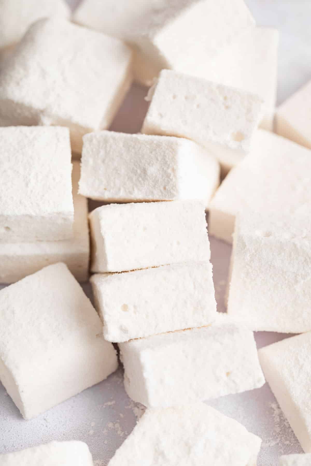 Pile of square homemade marshmallows on a white board.
