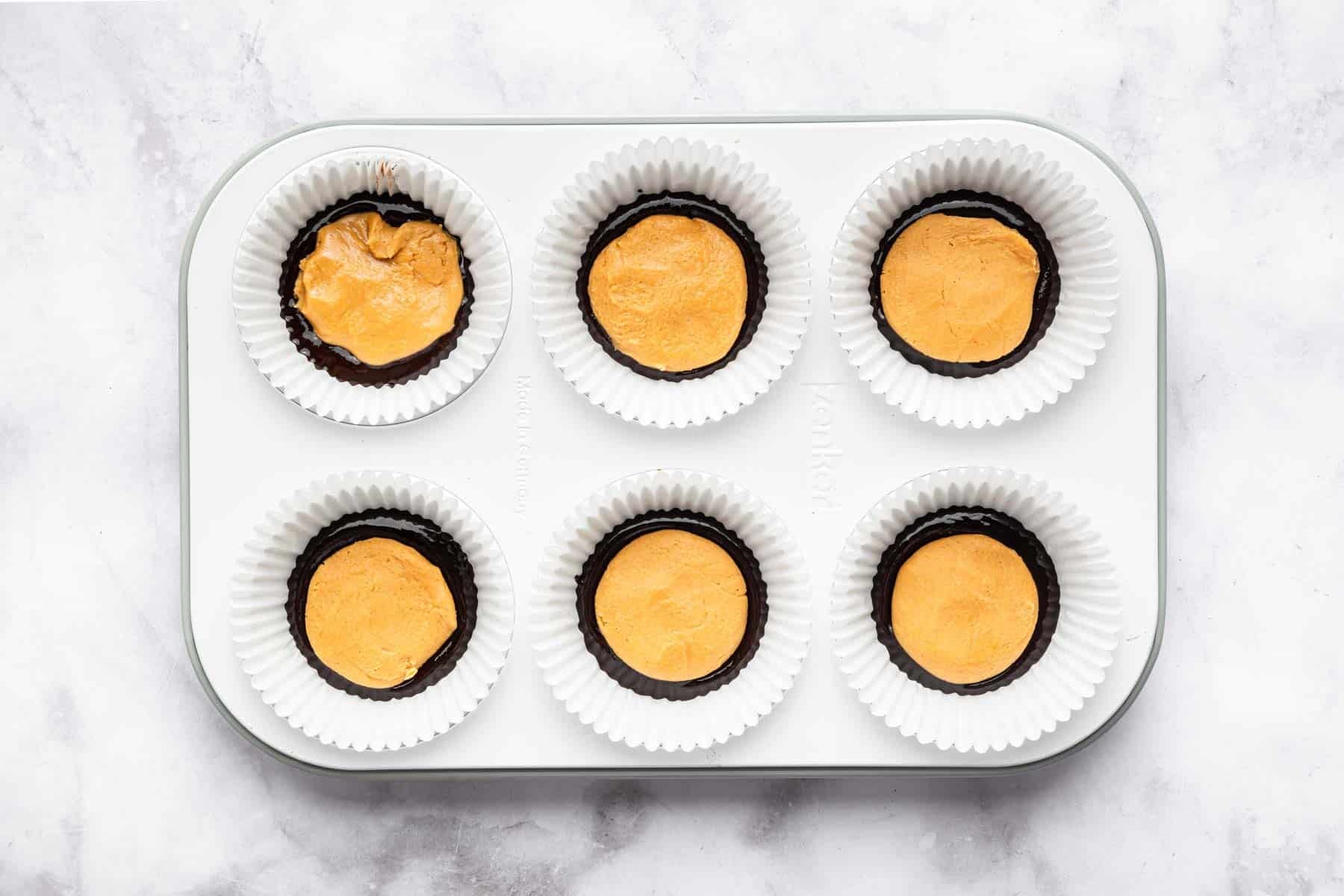 Light brown candy patties placed in a muffin tin.