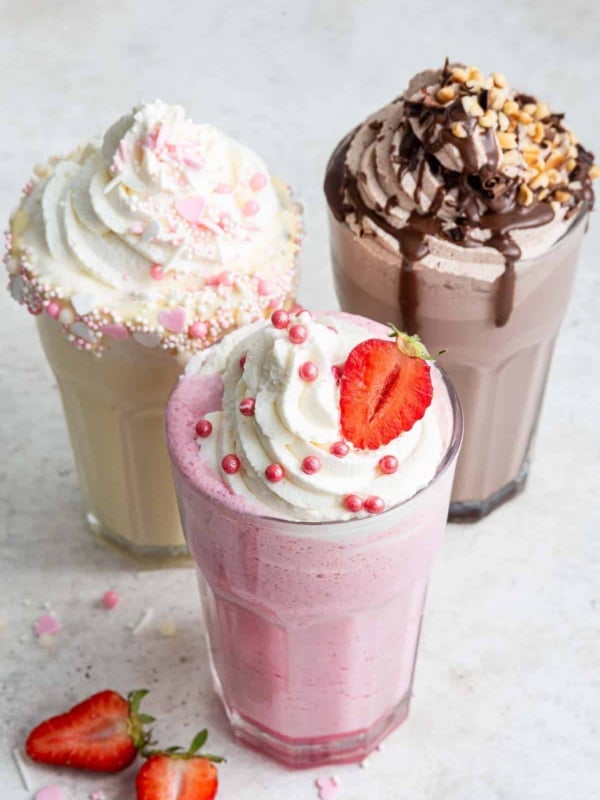 Image of 3 glasses of milkshakes: strawberry in front with chocolate and vanilla in the back.