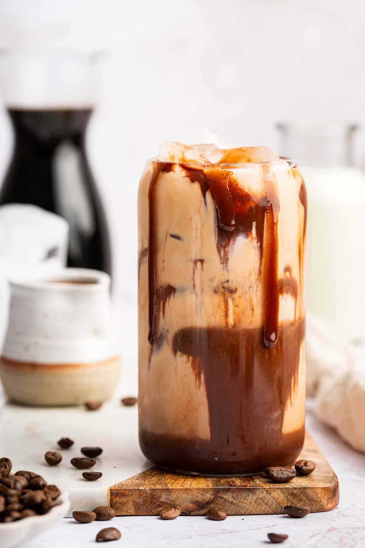 Vertical image of chocolate smeared iced mocha recipe with coffee beans.
