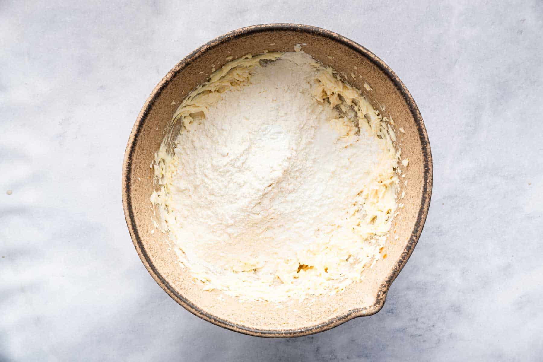 Fluffy white flour on top of pale yellow batter.