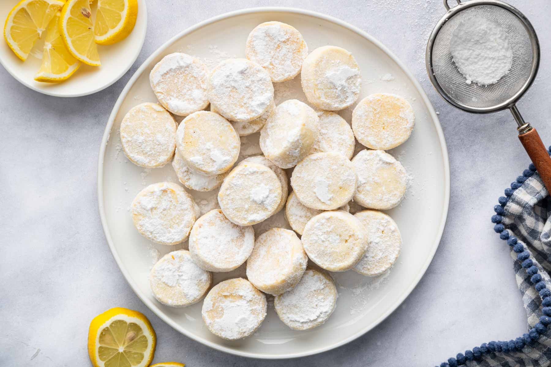 Round white plate with powdered sugar lemon meltaways stacked on top.