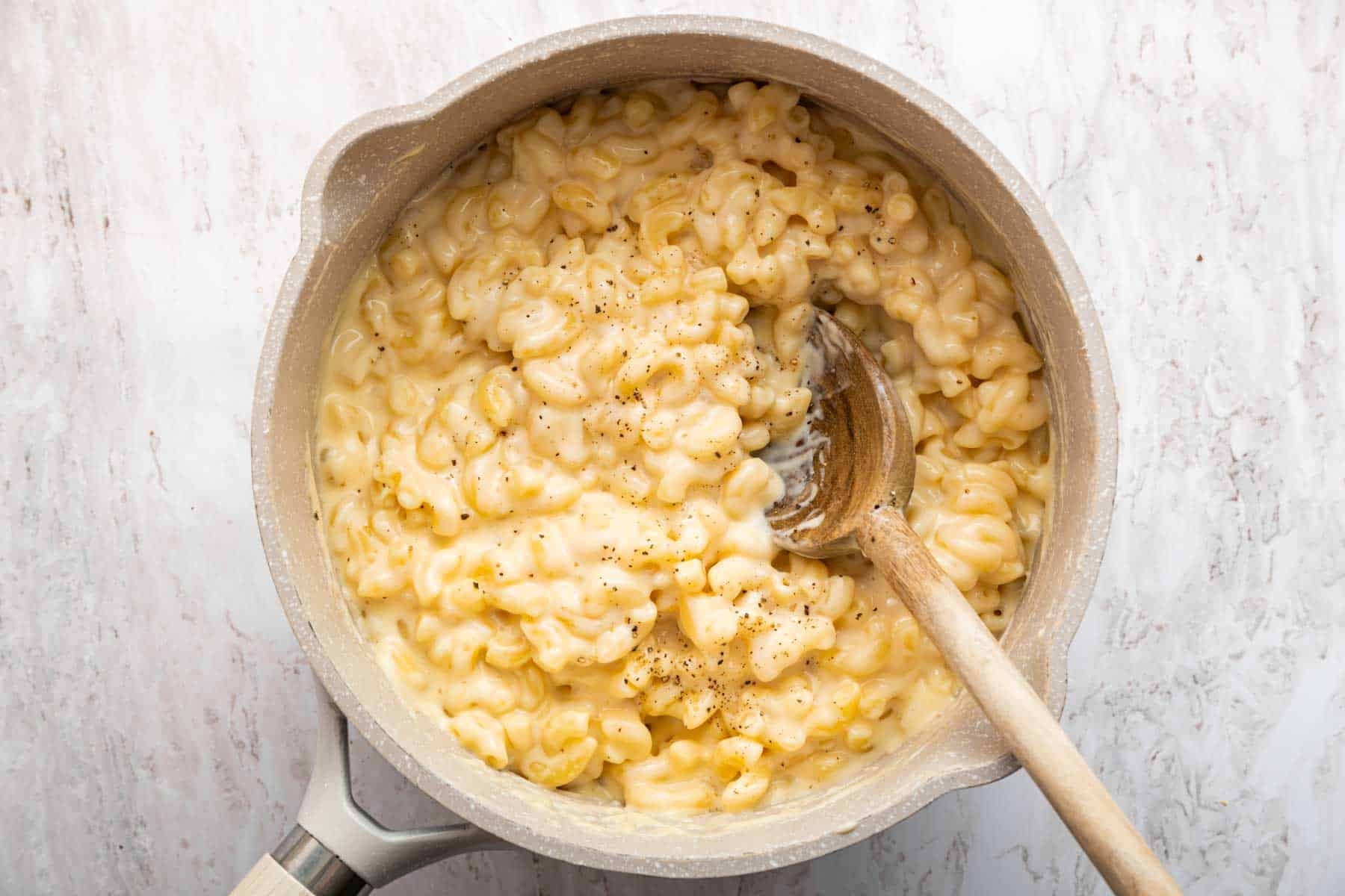 Mac and cheese for two in a small grey pot with wooden spoon.