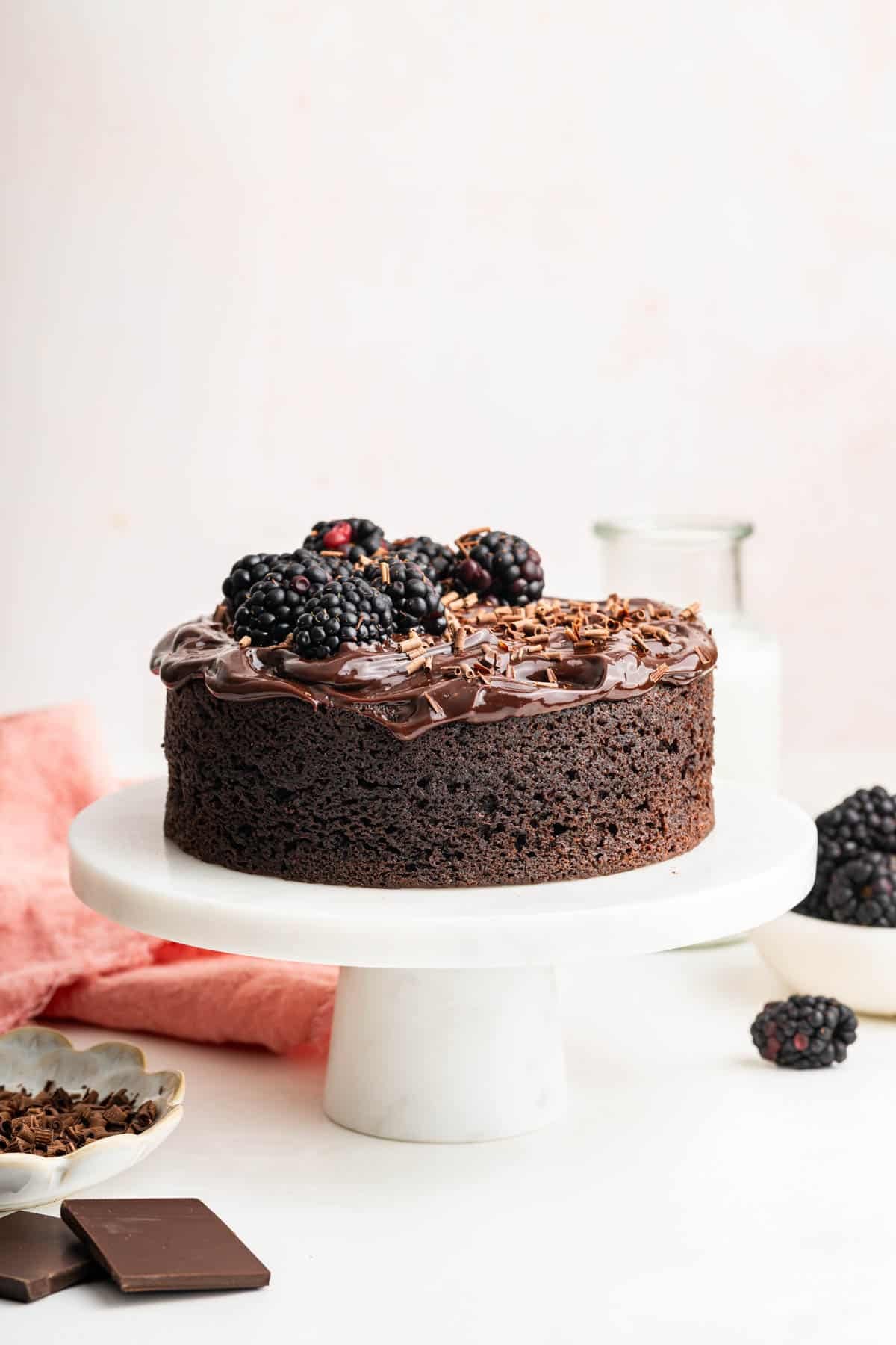Mini chocolate cake decorated with blackberries on a small white cake stand.