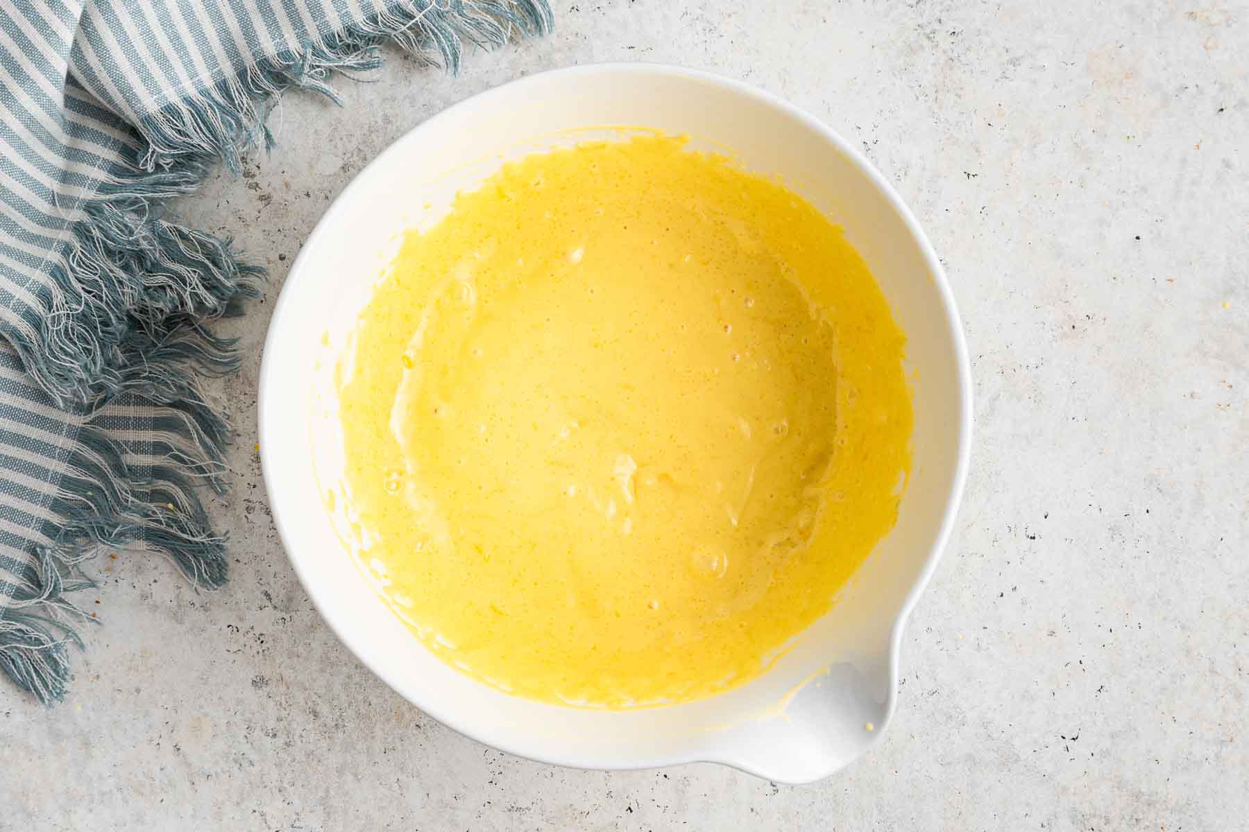 A white bowl containing mini lemon cheesecakes batter.