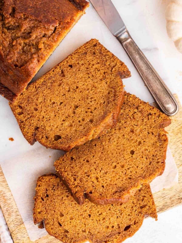 Overhead shot of three slices of pumpkin bread on cutting board.
