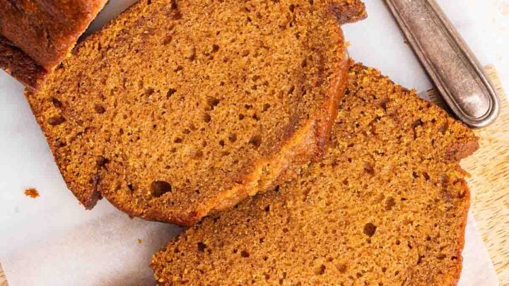 Overhead shot of three slices of pumpkin bread on cutting board.