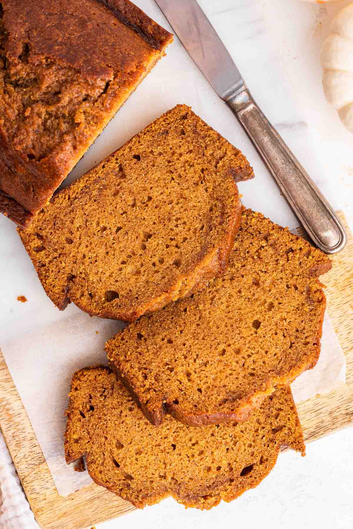 Overhead shot of three slices of pumpkin bread on cutting board.