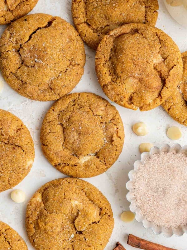 Overhead shot of orange pumpkin white chocolate chip cookies and cinnamon sticks.