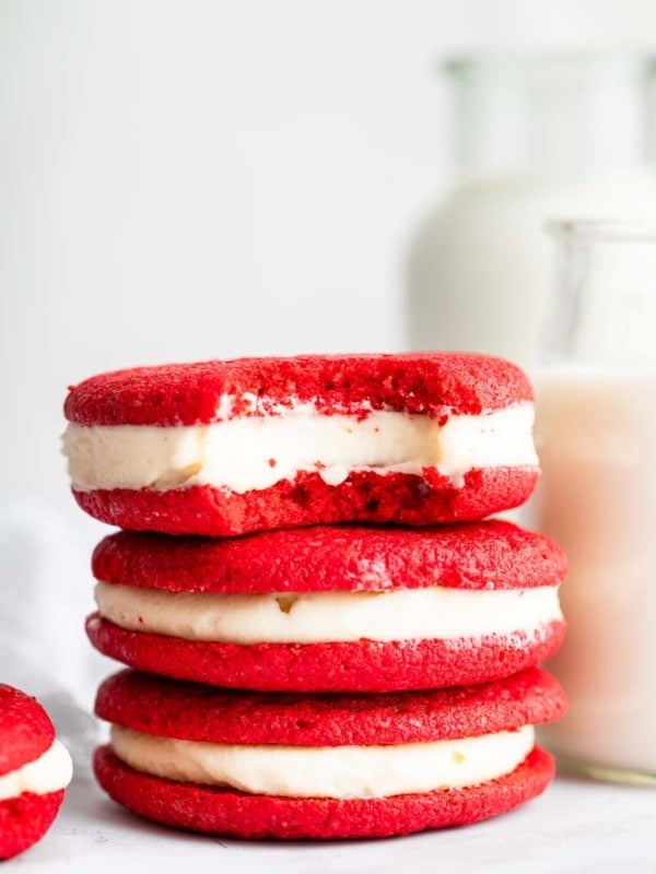 Stack of bright red cookies with white filling.