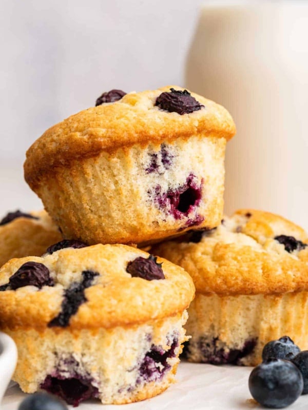 A small batch of four blueberry muffins stacked on top of each other.