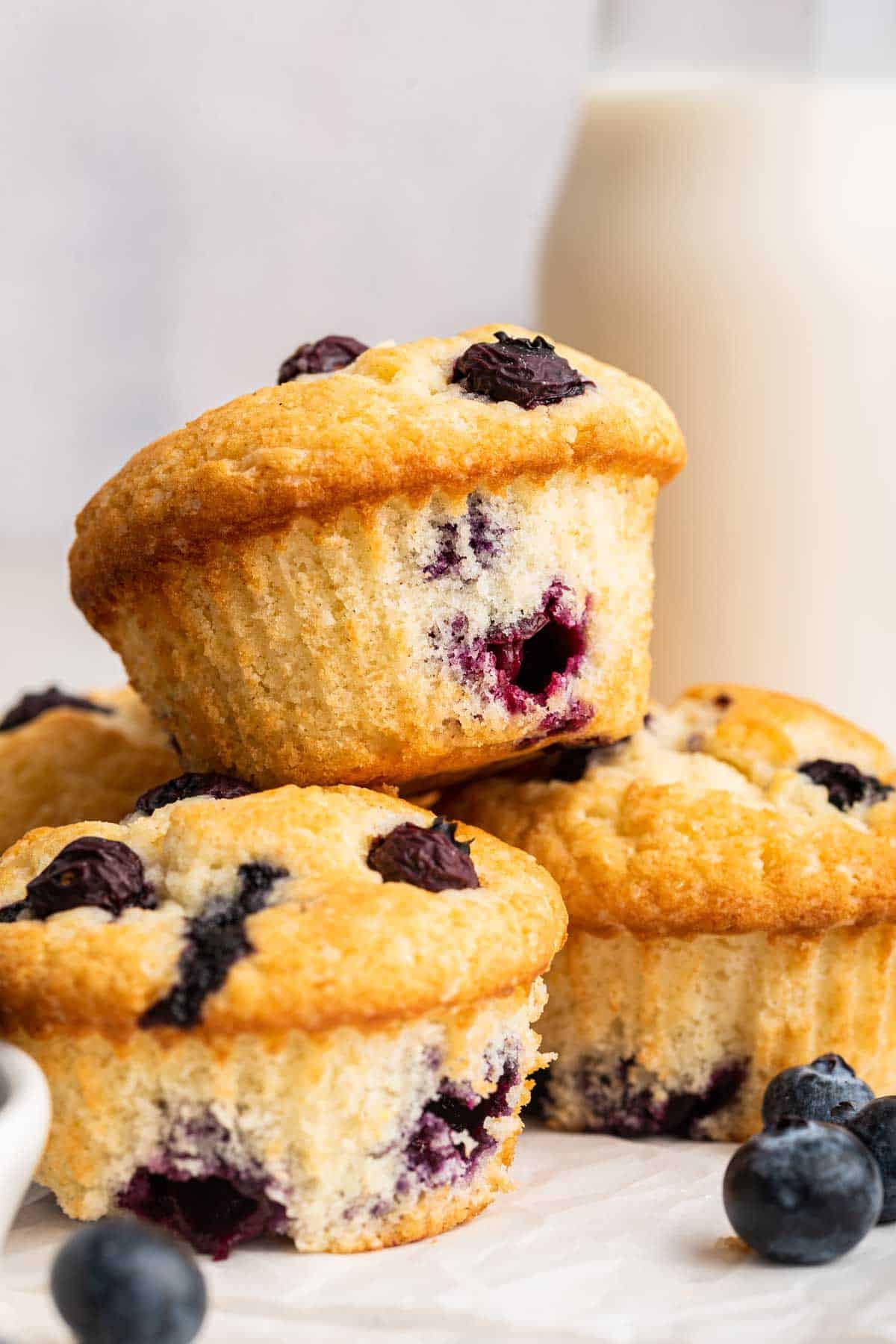 A small batch of four blueberry muffins stacked on top of each other.
