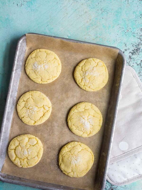 Six easy sugar cookies on baking sheet with turquoise background.