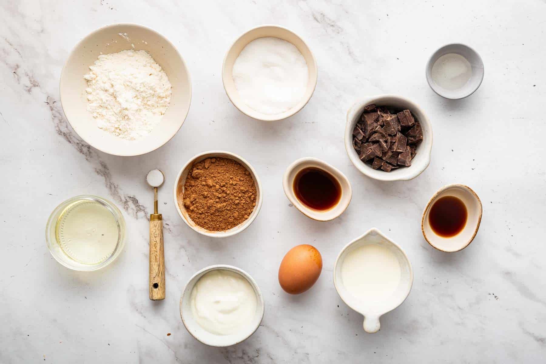 Lots of small bowls with baking ingredients on marble counter.