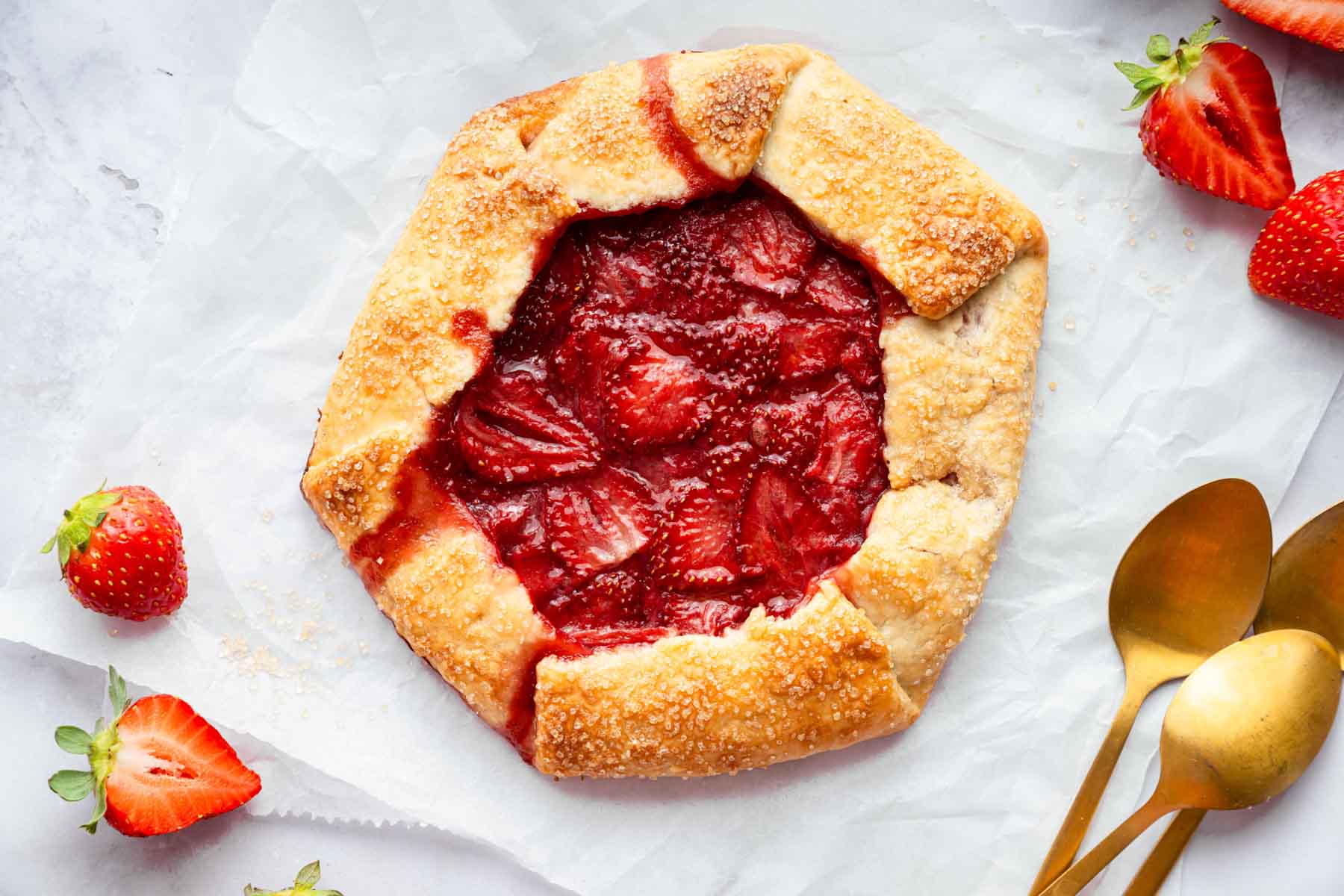Freshly baked strawberry galette with two spoons on side.