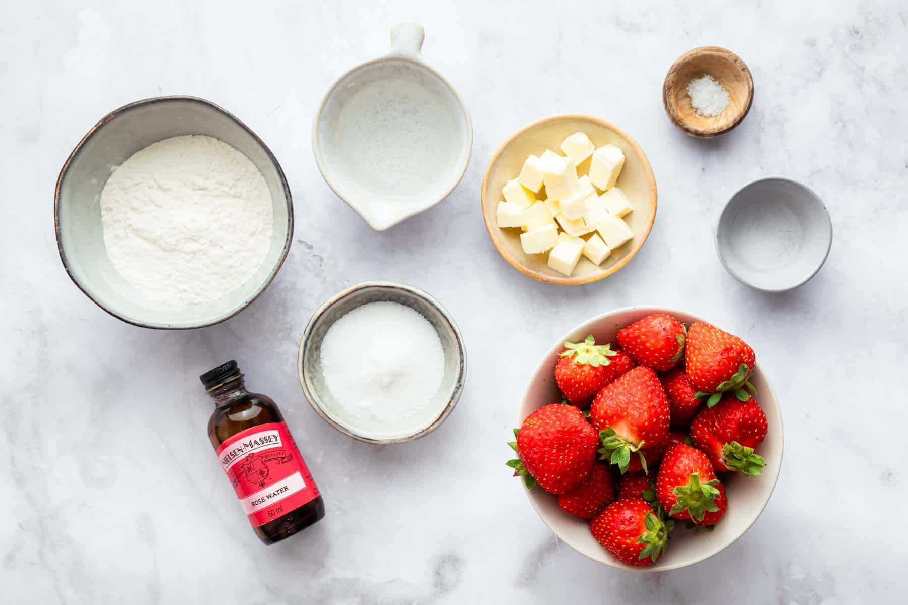 Small bowls of flour, sugar, diced butter, and whole strawberries.