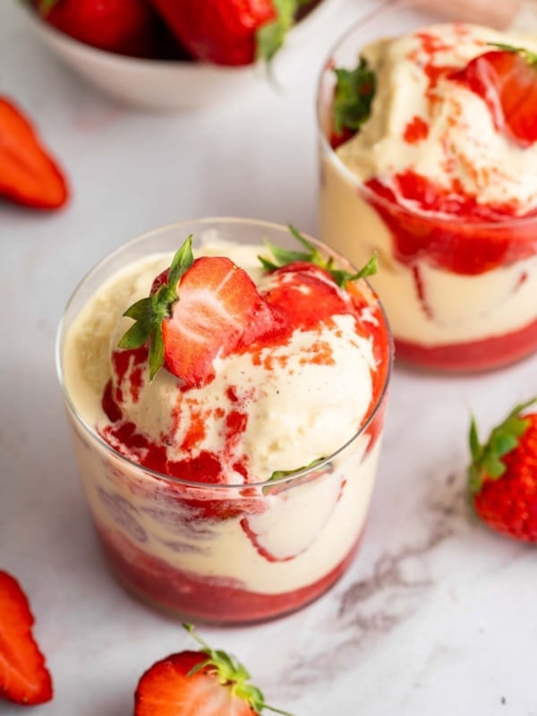 Two glass mugs full of a strawberry sundae.