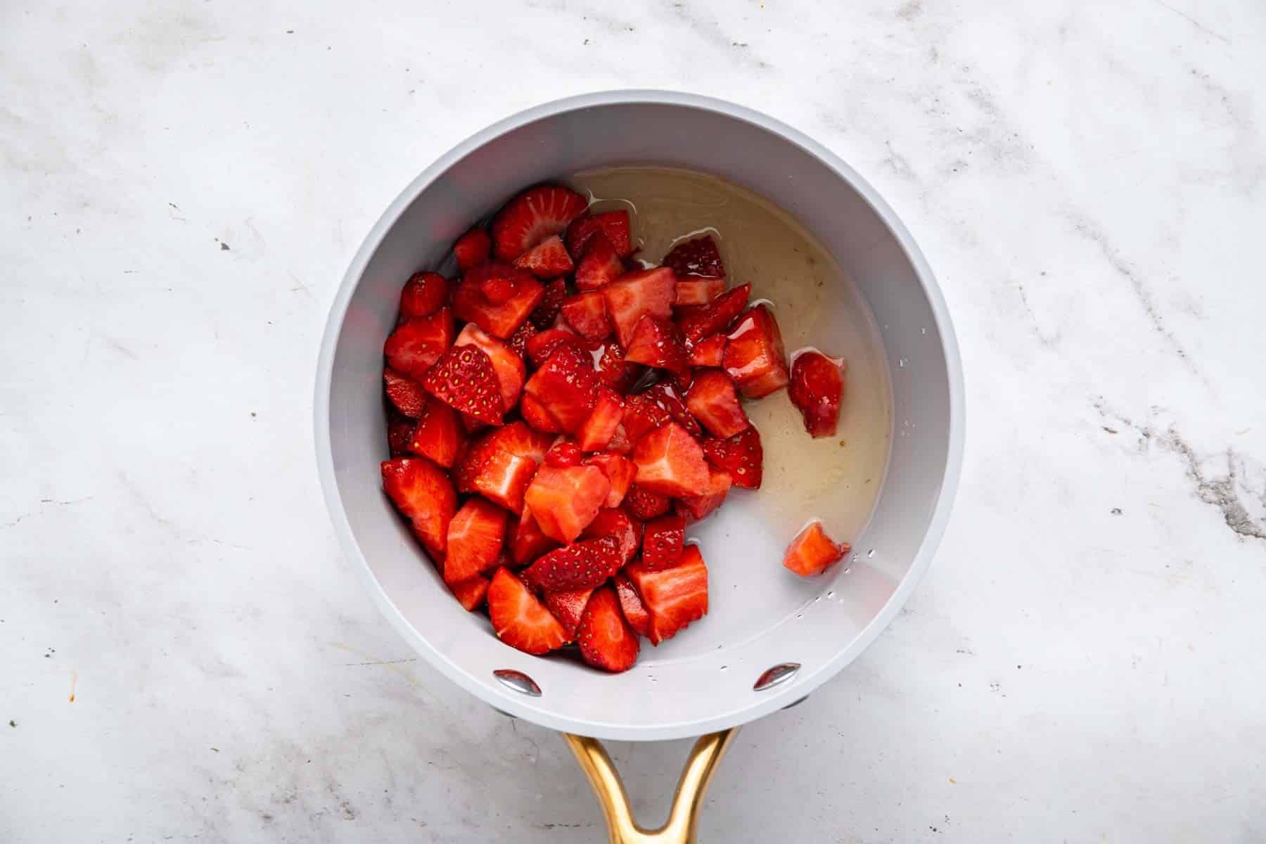 Fresh chopped red fruit in a small grey skillet.