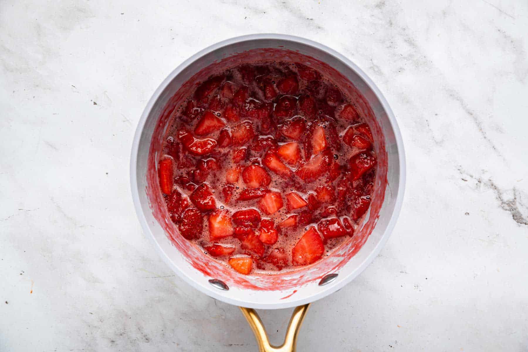 Cooked fruit bubbling in a small grey skillet.