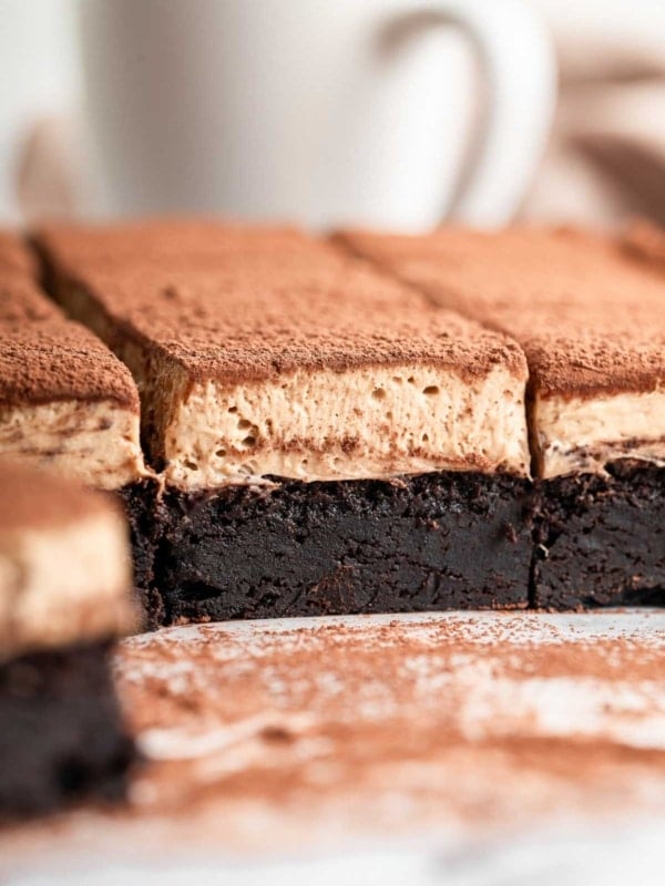 Tiramisu brownies cut from the side showing the rich brownie layer, fluffy top and cocoa powder dust.