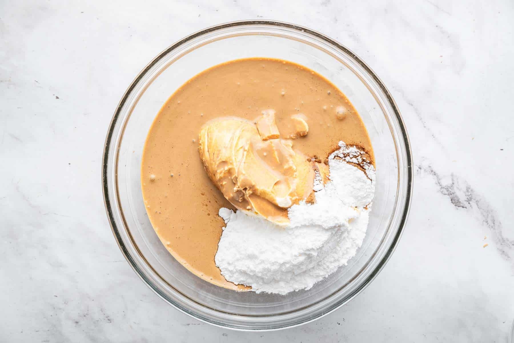 Glass bowl with melted brown coffee ice cream, cream cheese and powdered sugar on top.