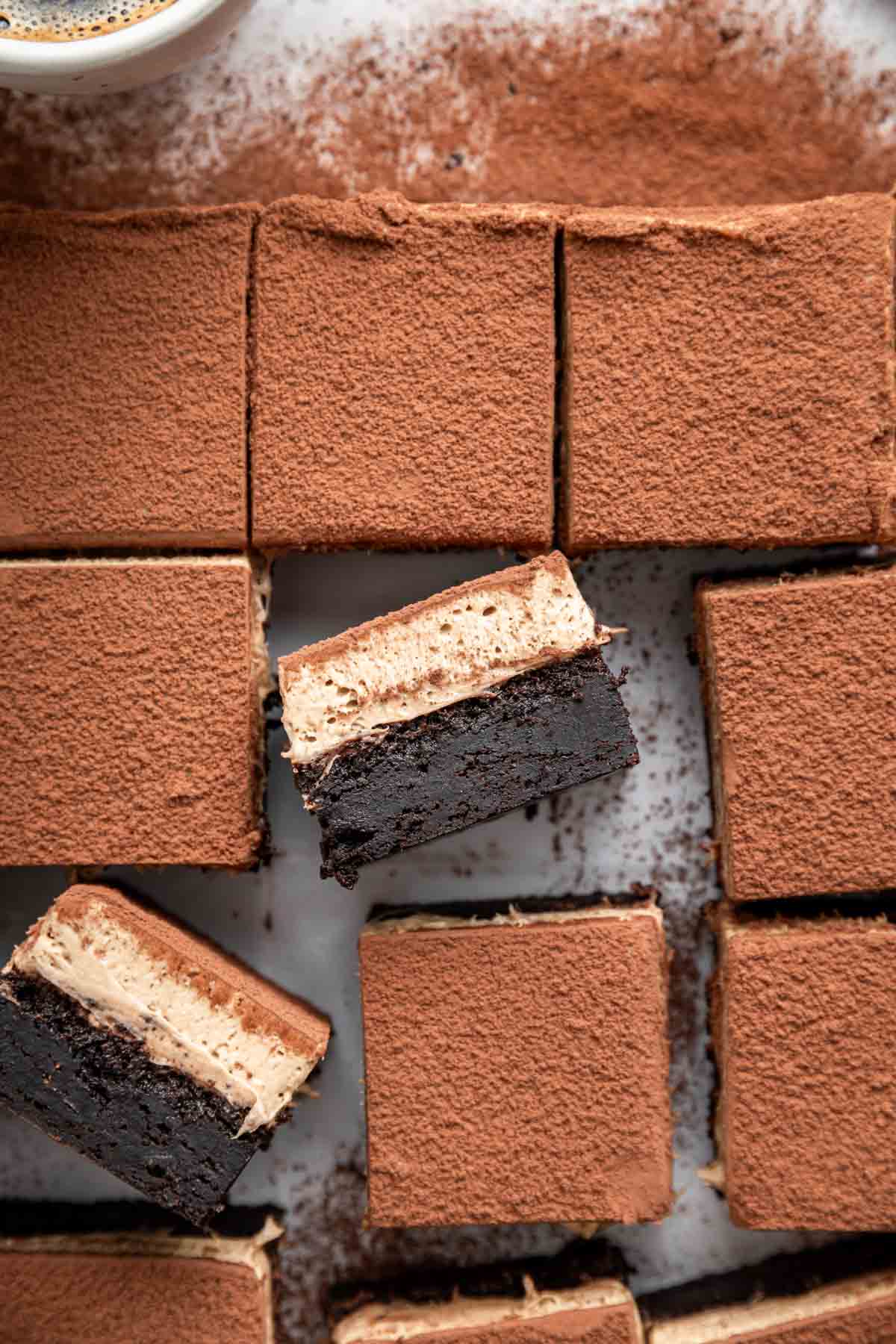 Vertical image of sliced tiramisu brownies with creamy top showing.