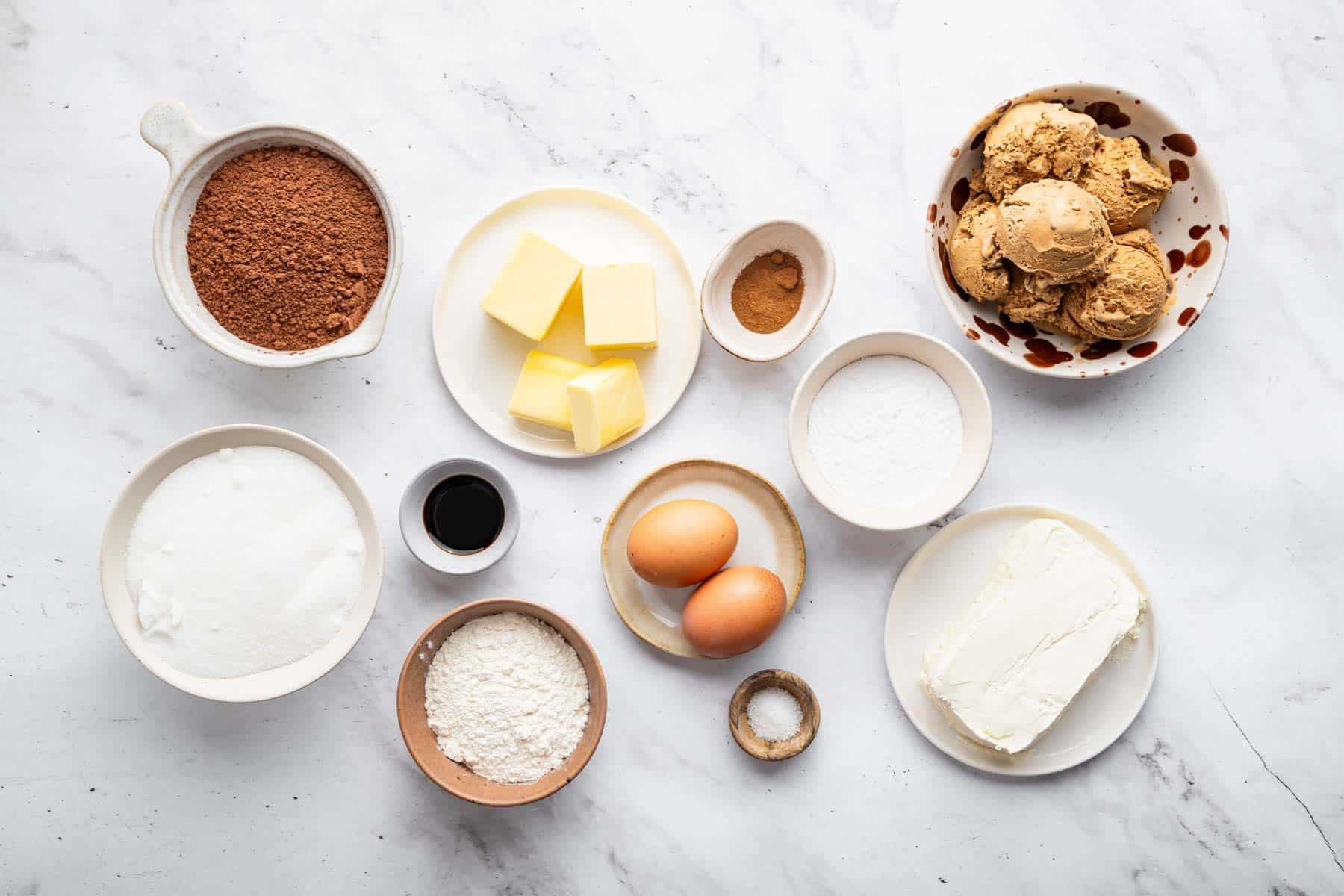 Small bowls with cocoa powder ,eggs, flour, and scoops of ice cream.