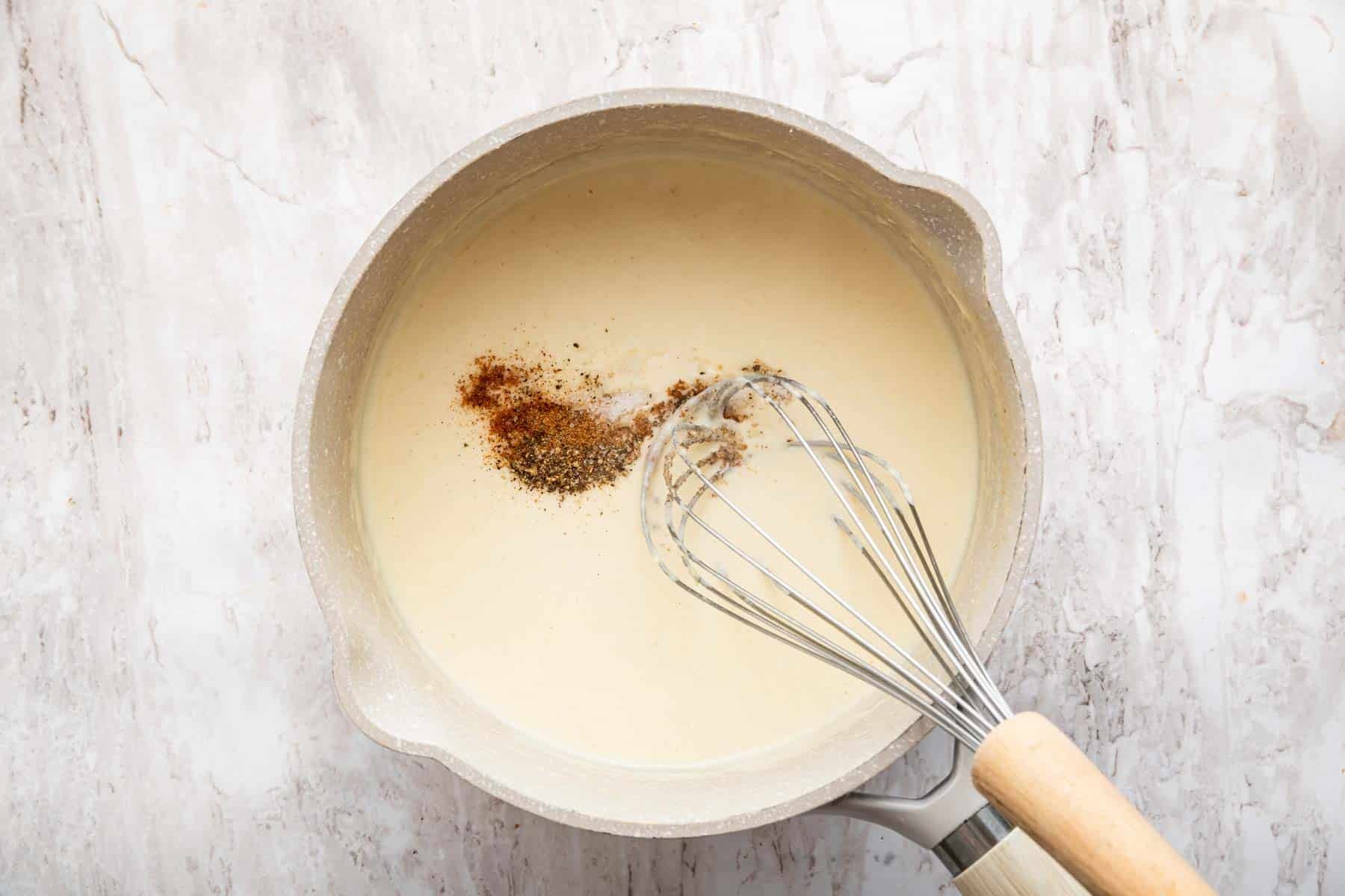 White sauce with salt, pepper, and nutmeg about to be whisked in.
