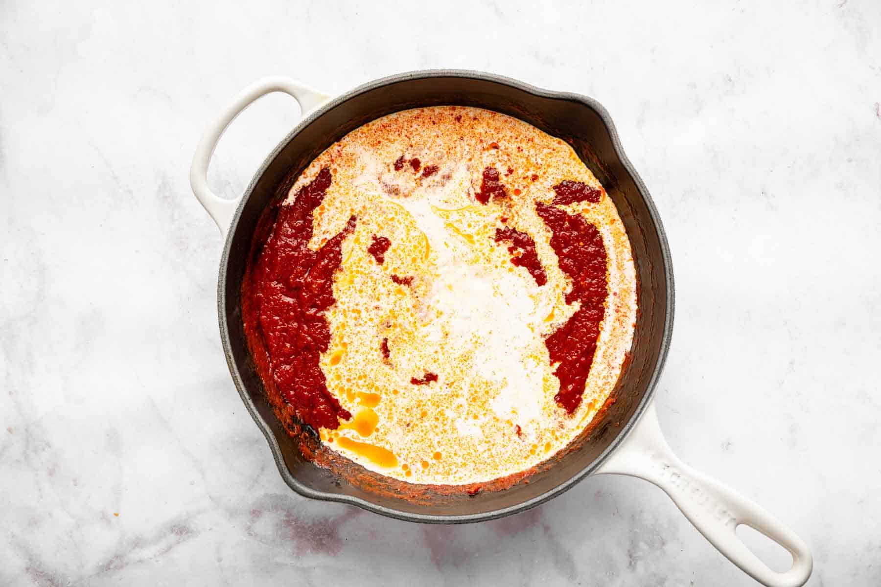 Cream splashed in a pan with red sauce.