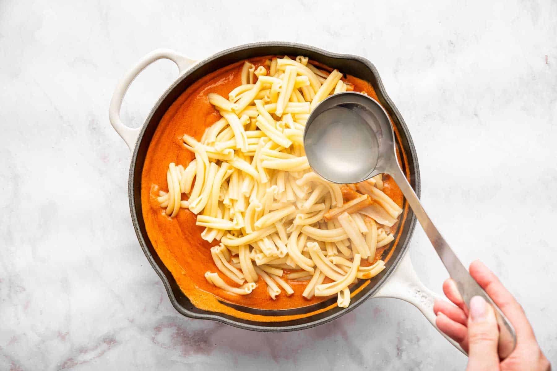 Plain pasta in orange sauce in a pan.