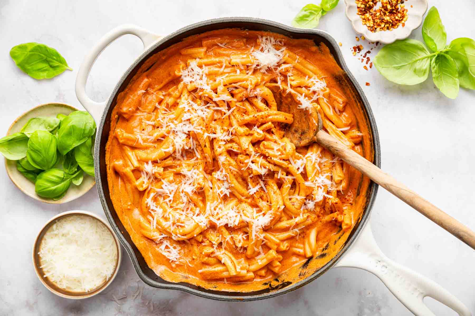Horizontal image of vodka pasta in skillet with wooden spoon.