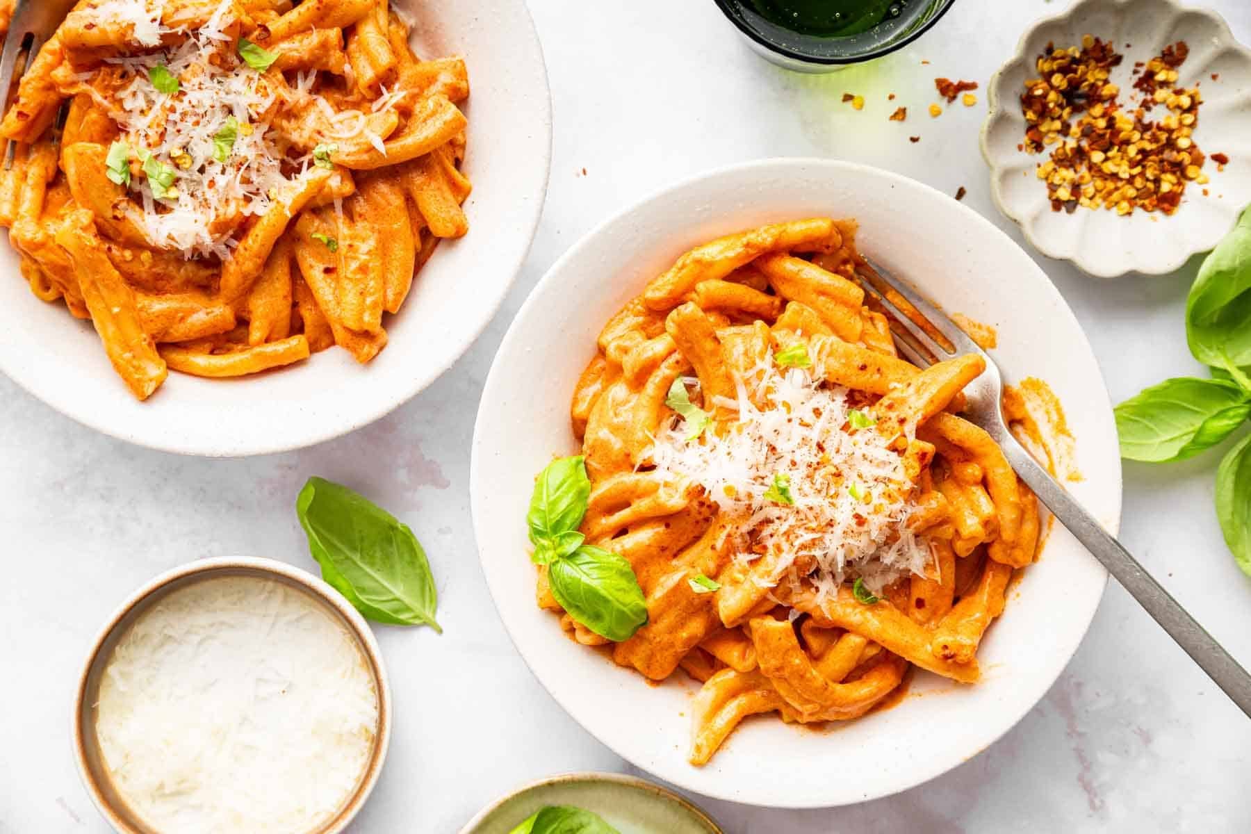 Two bowls of pasta alla vodka with parmesan on top.